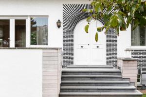 - une porte blanche sur une maison blanche avec des escaliers dans l'établissement De Pagode - A Serene Coastal Home with Pool, à Duinbergen