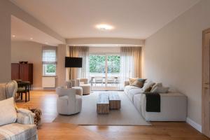 un salon avec des meubles blancs et une table dans l'établissement De Pagode - A Serene Coastal Home with Pool, à Duinbergen