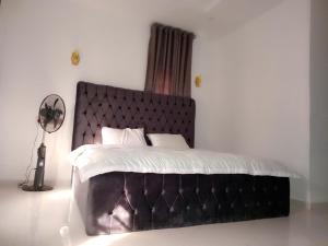 a bedroom with a large bed with a black headboard at Enis & Banky Home in Akure