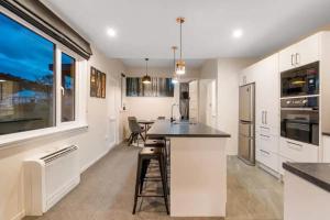 a kitchen with white cabinets and a large window at Quiet home with modern touch in Dunedin