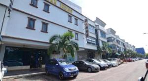una fila de autos estacionados frente a un edificio en Hotel Alam Indi, en Johor Bahru