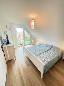 ein Schlafzimmer mit einem Bett, einem Fernseher und einem Fenster in der Unterkunft Neu Ferienhaus Sielbude Neßmersiel mit Garten und Wallbox allergikerfreundlich in Neßmersiel