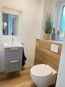 ein Badezimmer mit Toilette und Waschbecken in der Unterkunft Neu Ferienhaus Sielbude Neßmersiel mit Garten und Wallbox allergikerfreundlich in Neßmersiel