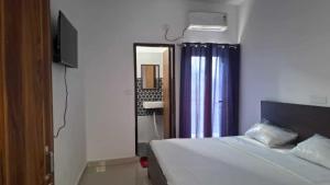 a bedroom with a bed and a mirror and a television at Hotel O SGT University Road Formerly Budhera in Dhankot