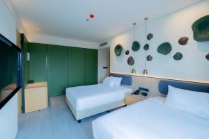two beds in a room with green walls at TMG Hotel Tebet, Marclan Collection in Jakarta +29 photos