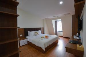 a bedroom with a bed and a desk with a laptop at Khách sạn Pine Hill Hotel Dalat in Da Lat