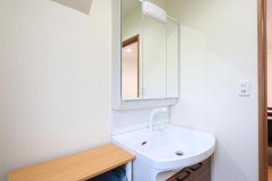 een witte badkamer met een wastafel en een spiegel bij コテージ鎌倉 in Fujikawaguchiko