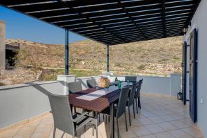 a wooden table and chairs on a patio with a view at Elysia House in Posidhonía