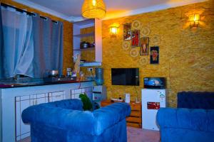 Hakuna Matata Gardens في Migori: غرفة معيشة بها كنب ازرق ومطبخ