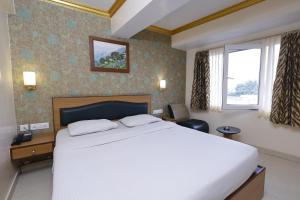 a bedroom with a large white bed and a window at Hotel Nahar Manchester Inn in Coimbatore