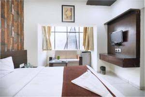 Un dormitorio con una cama y un televisor en una pared. en Hotel PALMVIEW RESIDENCY, en Vadodara
