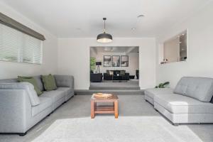 een woonkamer met twee banken en een salontafel bij Tihi Time - Great Deck Spa Pool & Games Room in Rotorua