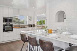 een witte keuken met een groot kookeiland met stoelen bij Tihi Time - Great Deck Spa Pool & Games Room in Rotorua