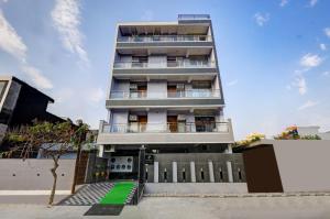 un alto edificio bianco con un prato verde davanti di Hotel La Corporate Suite a Noida