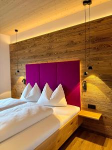 a bedroom with a white bed with a purple headboard at dein Dahoam Boutique Appartements in Gröbming