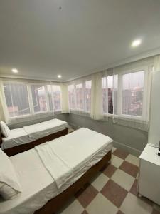 a bedroom with two beds and windows and a checkered floor at Ezel Group Hotel in Antalya +23 photos