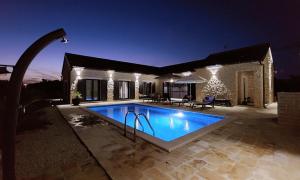 a swimming pool in front of a house at night at Luxury Villa Mala in Privlaka