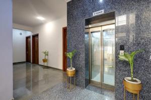 una hall con due piante in vaso e un ascensore di Hotel La Corporate Suite a Noida