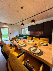 a dining room with a large wooden table and yellow chairs at dein Dahoam Boutique Appartements in Gröbming +27 photos