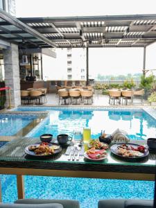 a table with plates of food next to a swimming pool at El Vistra Hotel Angeles in Angeles