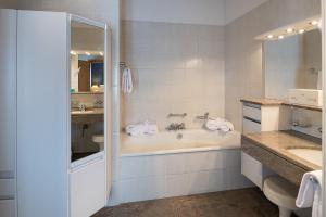 a white bathroom with a tub and a sink at Hotel Post in Bivio +35 photos