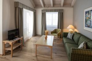 a living room with a green couch and a tv at Hotel Post in Bivio