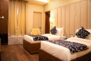 una habitación de hotel con dos camas y una silla en The Leon, en Srinagar 7 fotos más