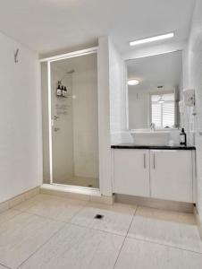 a white bathroom with a sink and a shower at Bright Ocean Horizon Escape in Noosa Heads +18 photos