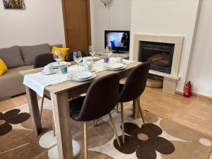 a dining table and chairs in a living room with a fireplace at Апартамент за гости 4а26 Планинска Магия Grand Monastery Пампорово in Pamporovo