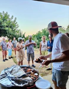 a man holding a plate of food on a grill at Camping du Vignal in Lablachère