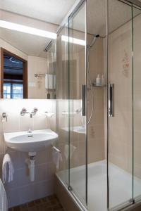 a bathroom with a shower and a sink at Hotel Post in Bivio