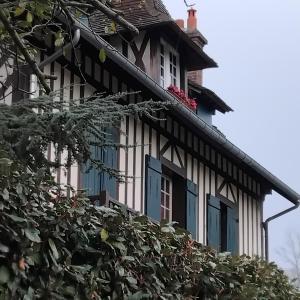 a house with blue windows and a tree at Le vieux pré de la motte in Villers-sur-Mer