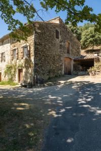 ein altes Steingebäude mit einem Tor und einer Einfahrt in der Unterkunft Mas XVIIIème au cœur de la Drôme provençale in Béconne