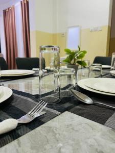 Una mesa con vasos, platos y cubiertos encima. en The Luxe Apartment, en Zanzíbar