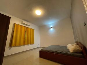 a bedroom with a bed and a yellow curtain at Villa SESSI in Abomey-Calavi
