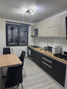 a kitchen with black cabinets and a table and chairs at Central Apartment KM 0 in Craiova