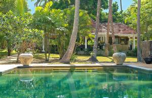 a swimming pool in front of a house with palm trees at Why House in Unawatuna