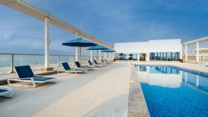 a pool on the roof of a building with chairs and umbrellas at Sea View Modern 2BHK Apartment with Balcony in Ras al Khaimah