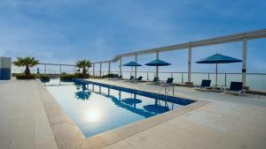 a swimming pool with chairs and umbrellas on a building at Sea View Modern 2BHK Apartment with Balcony in Ras al Khaimah