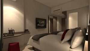 ein Schlafzimmer mit einem großen weißen Bett und Kissen in der Unterkunft Hotel Neo Kota Baru Parahyangan in Simpar