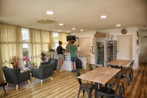 two people standing in a kitchen with tables and chairs at The Originals Access, Hôtel Le Lutéa in Riom-ès-Montagnes