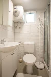 a white bathroom with a toilet and a sink at Seaview Beach Camp Maslina in Biograd na Moru