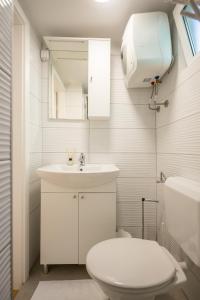 a white bathroom with a toilet and a sink at Seaview Beach Camp Maslina in Biograd na Moru +25 photos