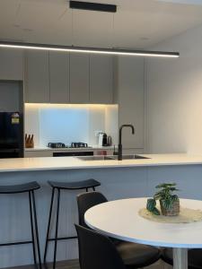 Waterfront High Rise 5 Beds 2 Car Parks في سيدني: مطبخ مع طاولة وكراسي ومغسلة