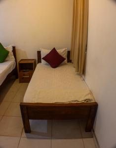 - une petite chambre avec un lit et un oreiller rouge dans l'établissement Villa by Wilpattu Nature Resort, à Murandanveli