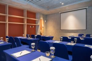 a conference room with blue tables and chairs and a screen at TMG Hotel Tebet, Marclan Collection in Jakarta