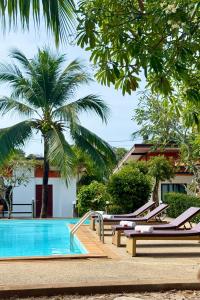 a pool with lounge chairs and a palm tree at Lanta Nesta Resort in Ko Lanta Yai