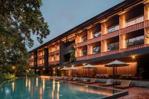 un hotel con piscina con sillas y sombrillas en Titik Dua, en Ubud