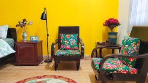 a living room with two chairs and a yellow wall at Tiny Garden House Cat Ba in Cat Ba