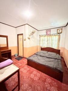 a bedroom with a bed and a table and a window at Singxay guesthouse ເຮືອນພັກສິງໄຊ 